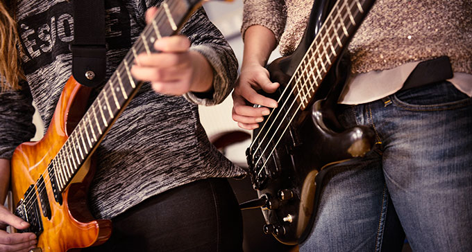 Två unga tjejer spelar elgitarr och elbas. Foto: Moa Karlberg